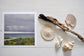 Pinch River unframed 17cm x 17cm Photographic Print on Paper Titled: Storm Clouds. The subject of the print is storm clouds over the ocean. Top view with sea shells and driftwood next to it to style the product image.
