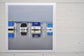 Photographic Print on Paper Titled: Lakeside Harmony. The subject of the print is 4 boats docked at a marina all with blue canopies and reflections on the still lake water. Top view.