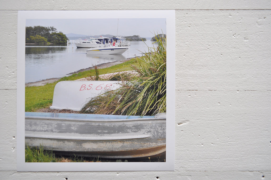 Pinch River unframed 17cm x 17cm Photographic Print on Paper Titled: Tinnies on the Shore. The subject of the print is a couple of tinnies on the lake shore with boats in the water in the background. Top view.