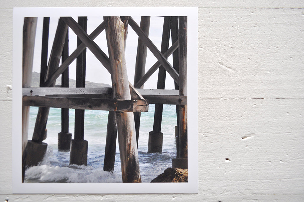 Pinch River unframed 17cm x 17cm Photographic Print on Paper Titled: Underneath the Jetty #4. The subject of the print is a close-up of the iconic Catherine Hill Bay Jetty from underneath, with the weather-worn timber pilings. Top view.