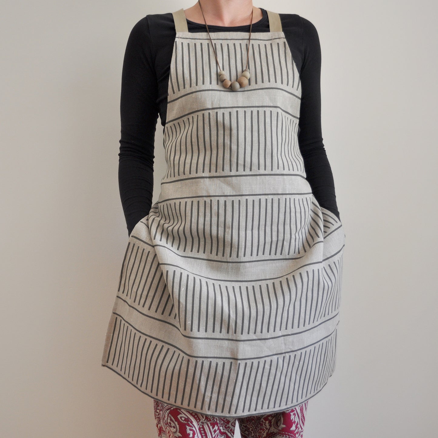 Model wearing Pinch River bib apron / full apron in Corduroy Pathway print against a plain background. Front View.