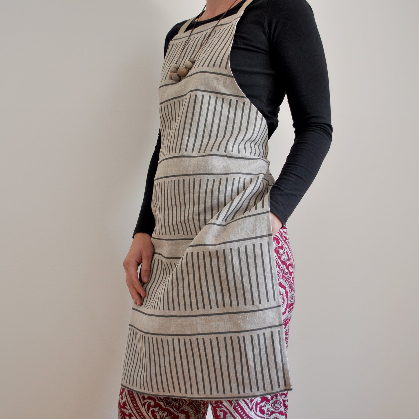 Model wearing Pinch River bib apron / full apron in Corduroy Pathway print against a plain background. Side View.