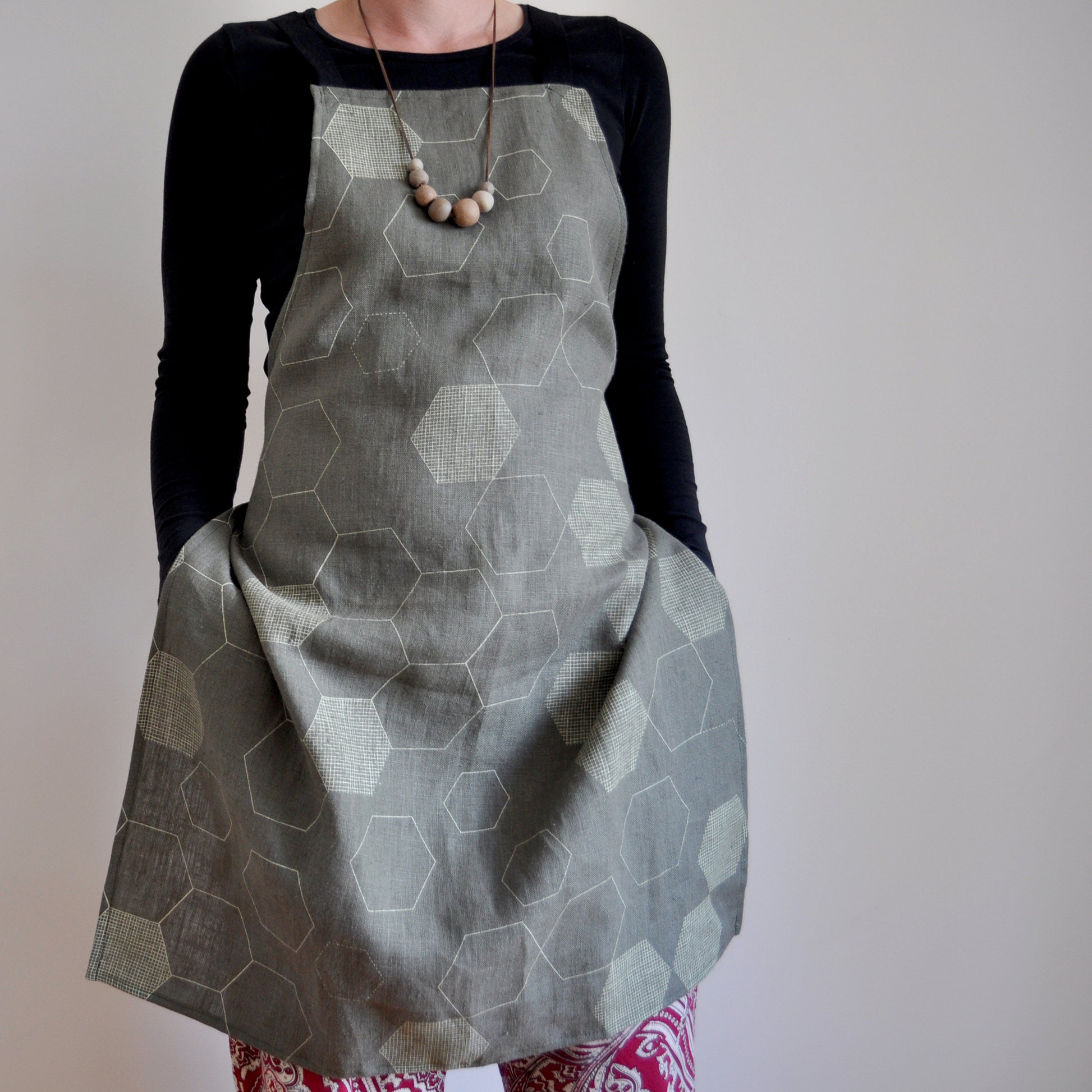 Model wearing Pinch River bib apron / full apron in Honeycomb print against a plain background. Front View.