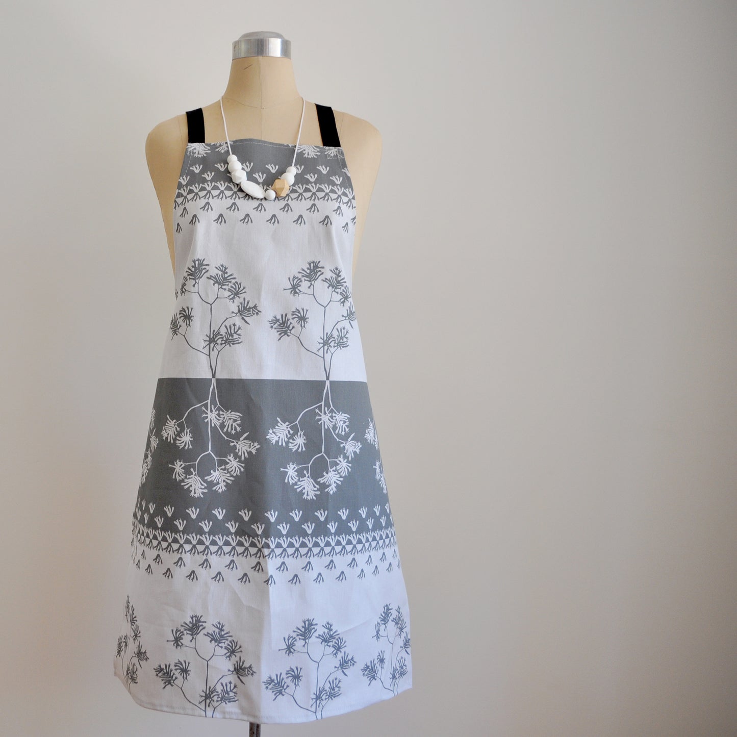 Pinch River bib apron / full apron in Kangaroo Paw print, Tempest on Silver Ash (colourway 3) on dressmakers dummy against a plain background. Front View.