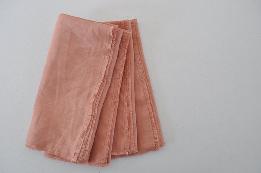 Set of 4 folded Pinch River pure linen napkins in Coral. Top view.