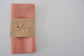 Set of 4 Pinch River pure linen napkins in Coral a branded belly band / product sleeve. Top view.