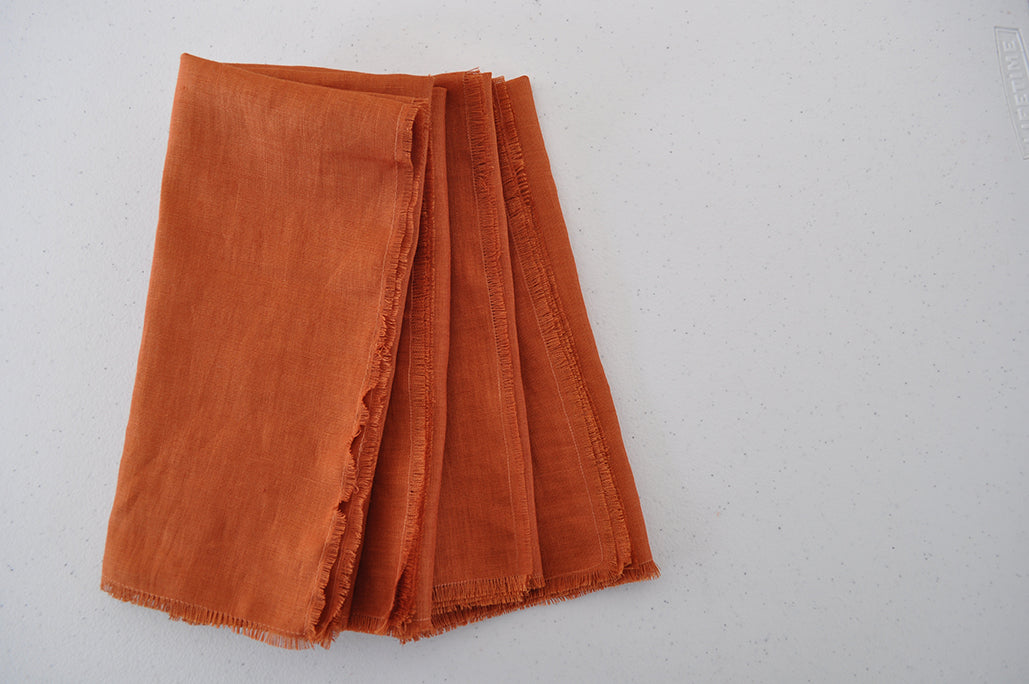 Set of 4 folded Pinch River pure linen napkins in Rust. Top view.