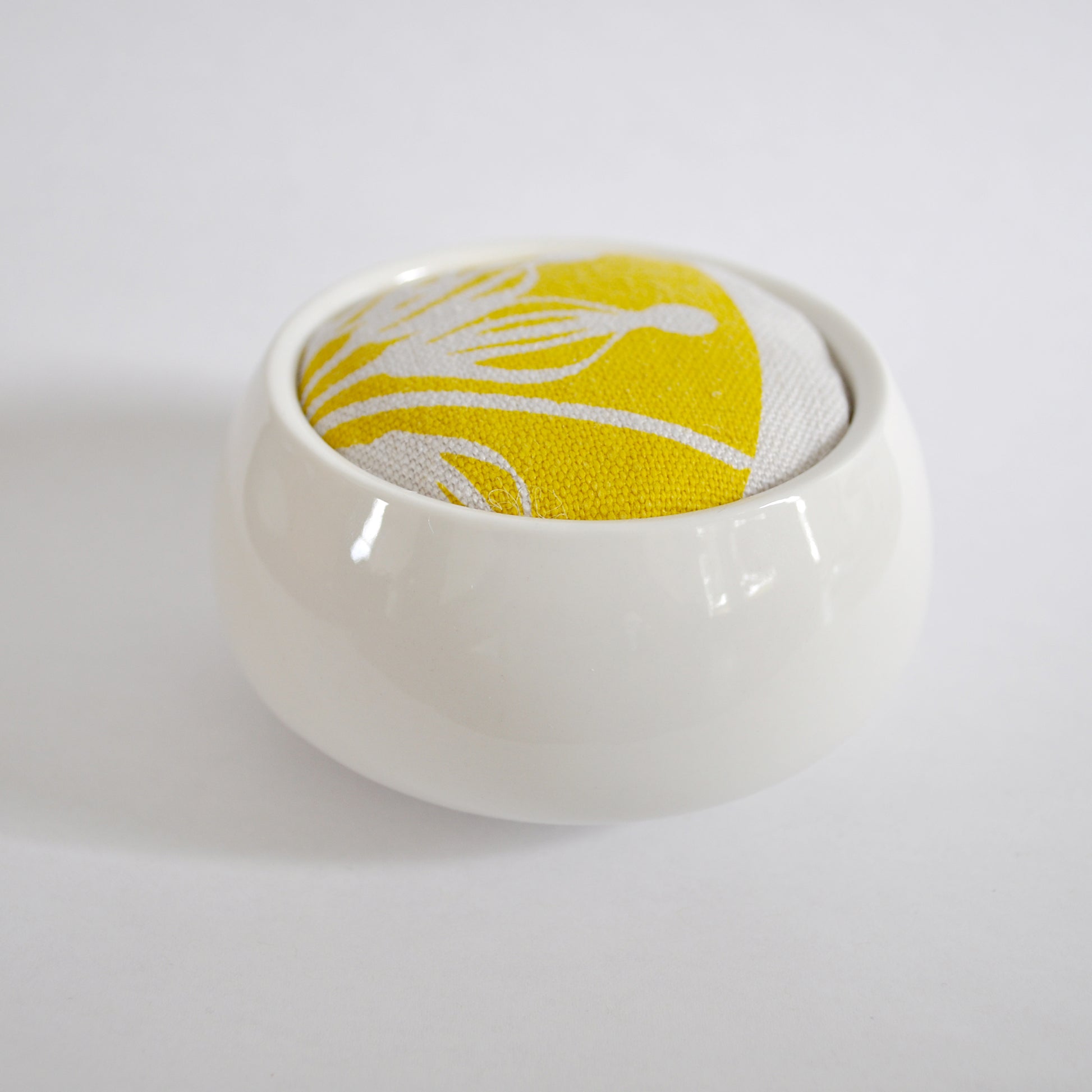 Pinch River ceramic pin cushion featuring Firewheel print in Buddha Gold (colourway 1_v2). Side view.