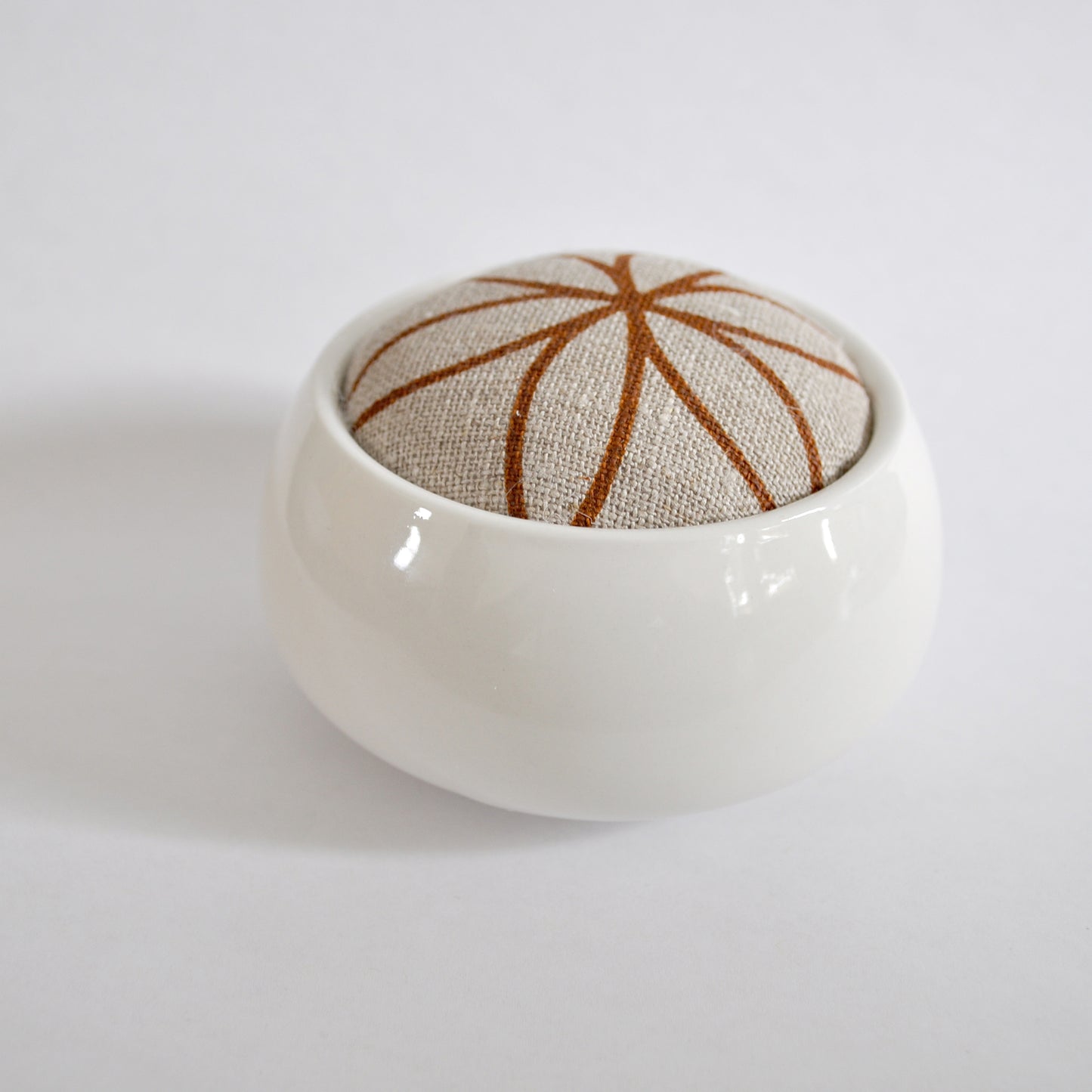 Pinch River ceramic pin cushion featuring Flower of Life print in Burnt Oragne (colourway 2). Side view.