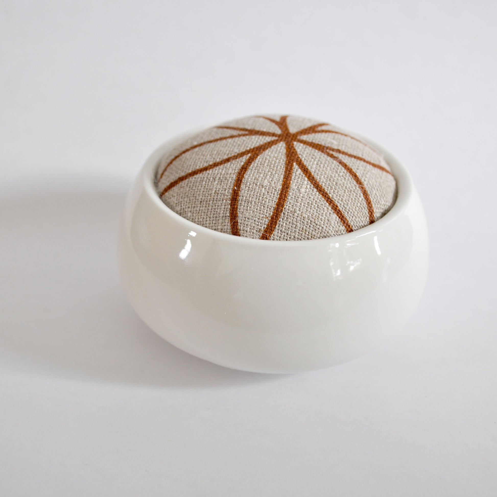 Pinch River ceramic pin cushion featuring Flower of Life print in Burnt Oragne (colourway 2). Side view.