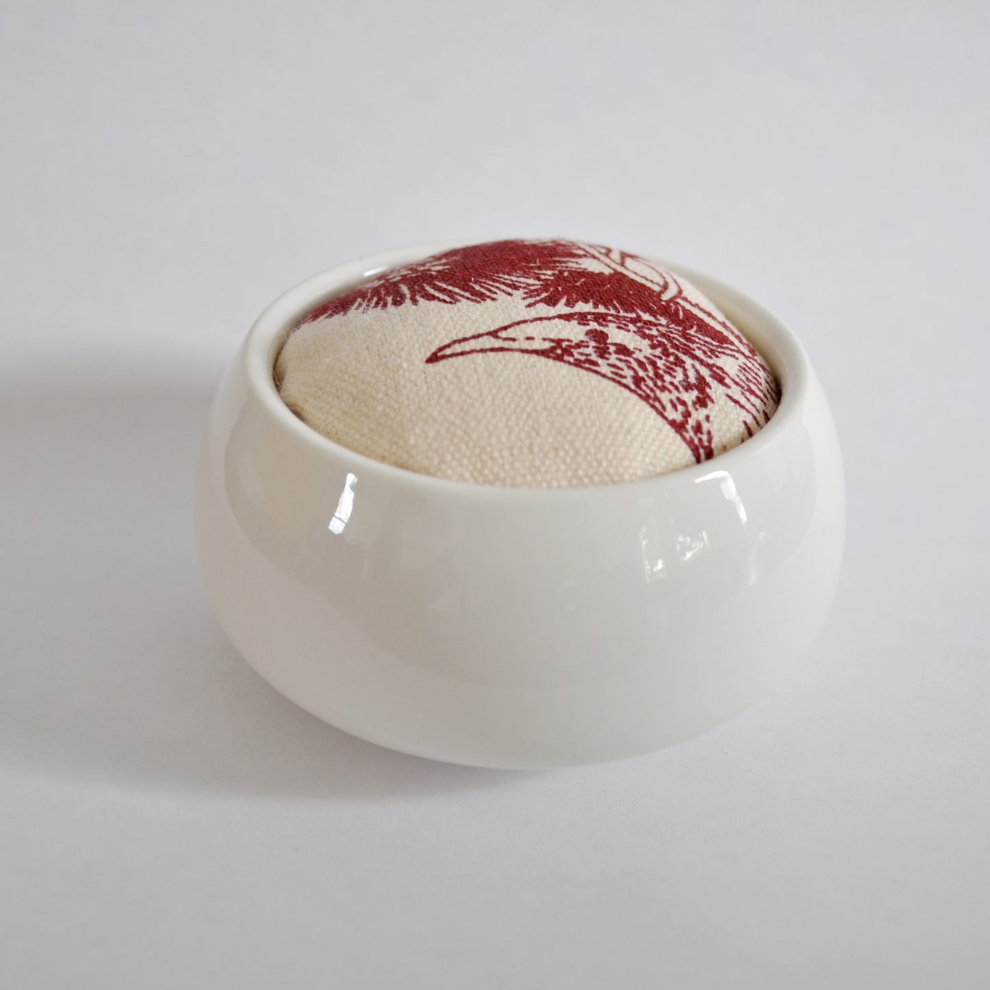 Pinch River ceramic pin cushion featuring Wattle Bird print in Wine Berry (colourway 1). Side view.