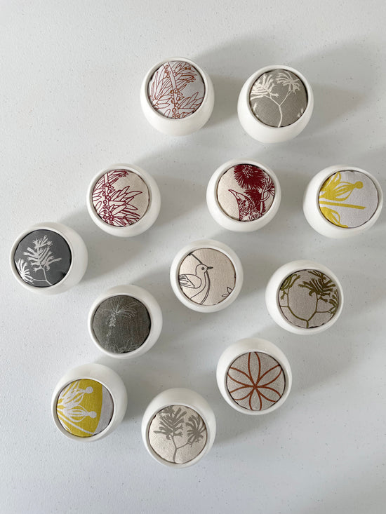 A collection of Pinch River ceramic pin cushions with various printed textiles. Top view.
