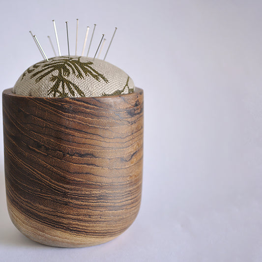 Pinch River teak pin cushion featuring Kangaroo Paw print in Desert Green (colourway 1). Side view. Product image is styled with pins.
