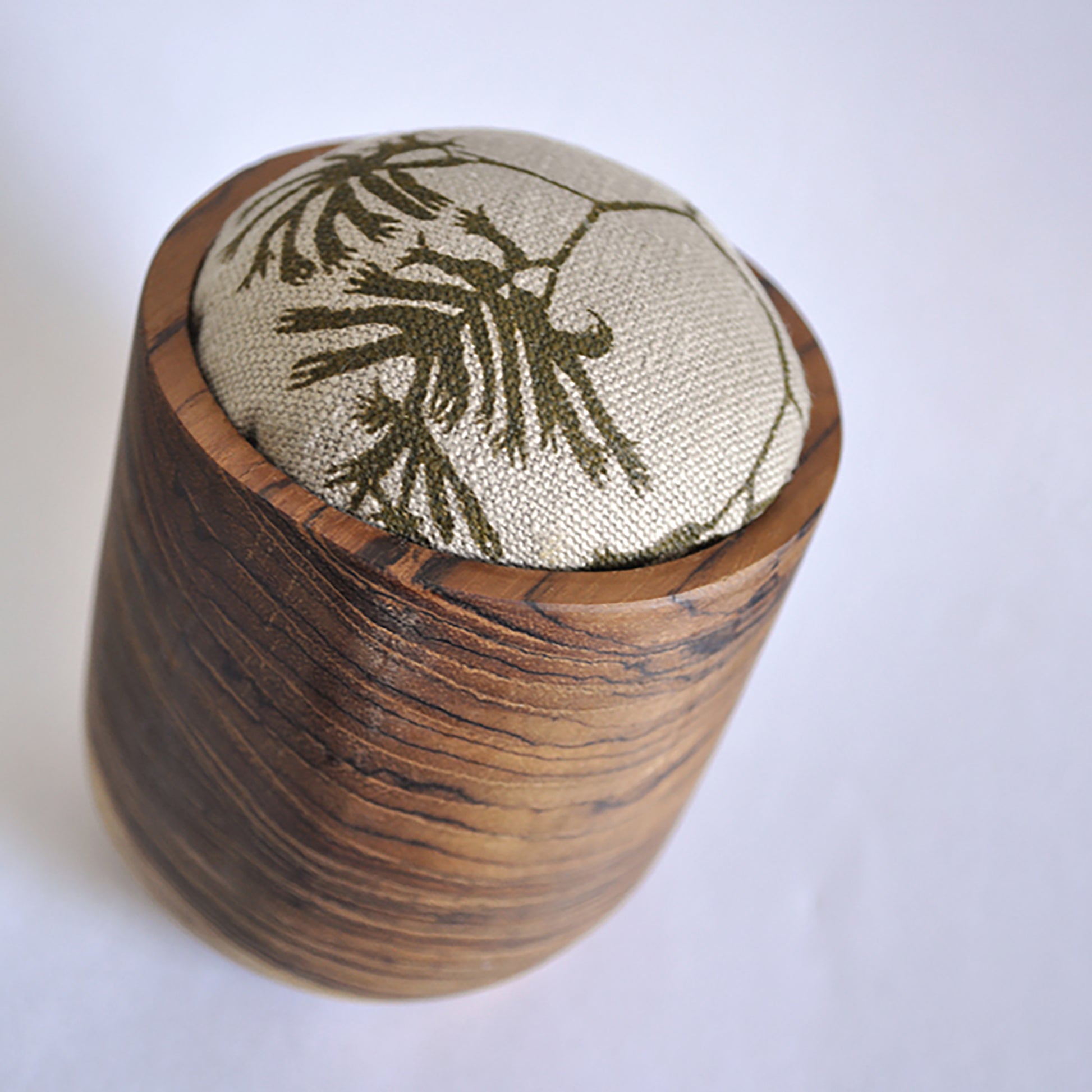 Pinch River teak pin cushion featuring Kangaroo Paw print in Desert Green (colourway 1). Angled view.