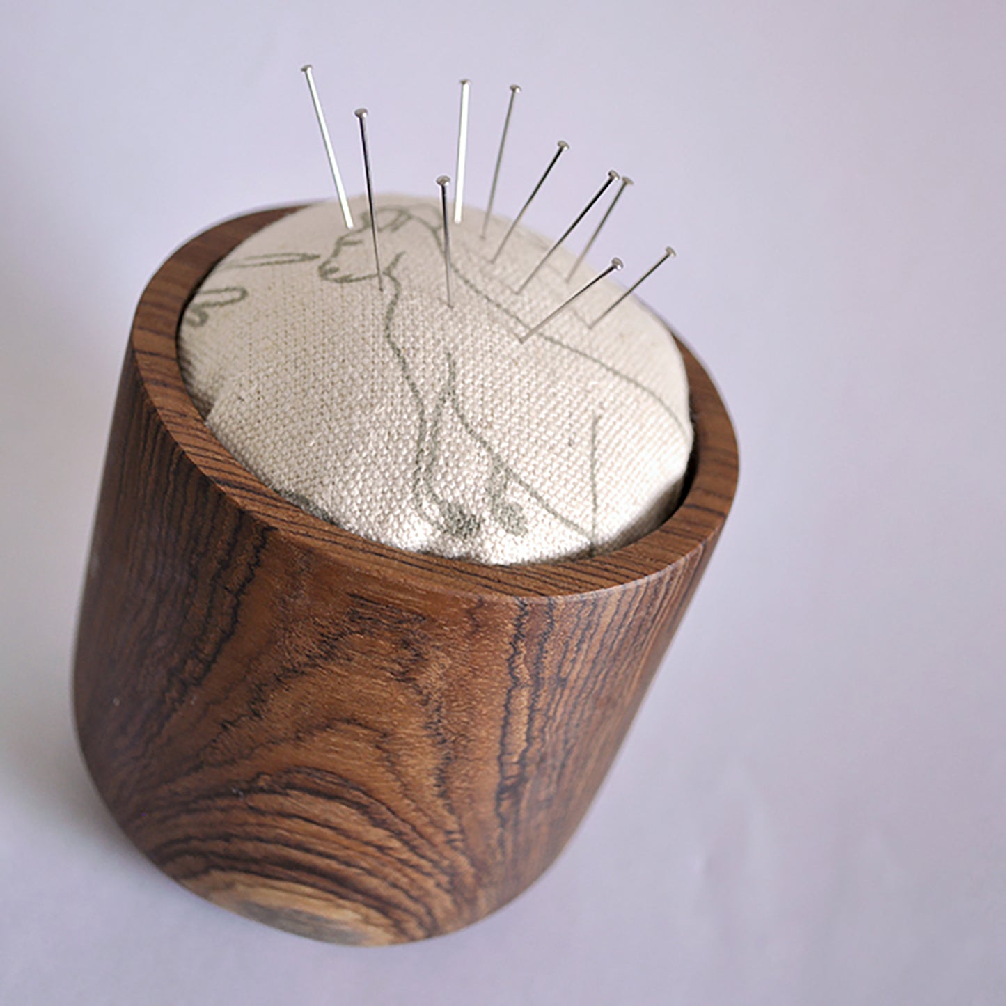 Pinch River teak pin cushion featuring Kangaroos print in Moss Green (colourway 2). Angled view. Product image is styled with pins.