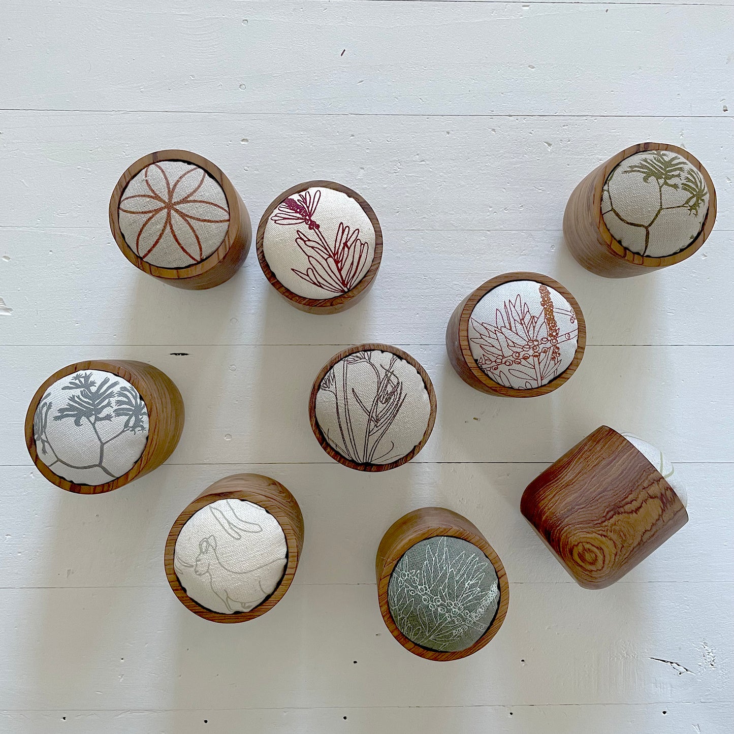 A grouping of Pinch River teak pin cushions.