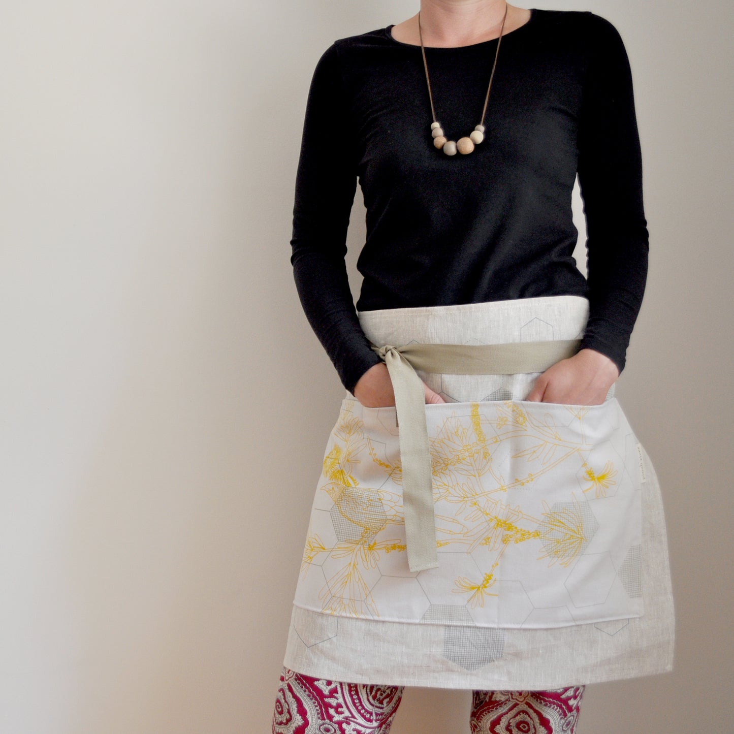 Model wearing Pinch River waist apron / half apron No. 1 with pockets, against a plain background. Front View.
