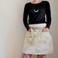 Model wearing Pinch River waist apron / half apron No. 1 with pockets, against a plain background. Front View.