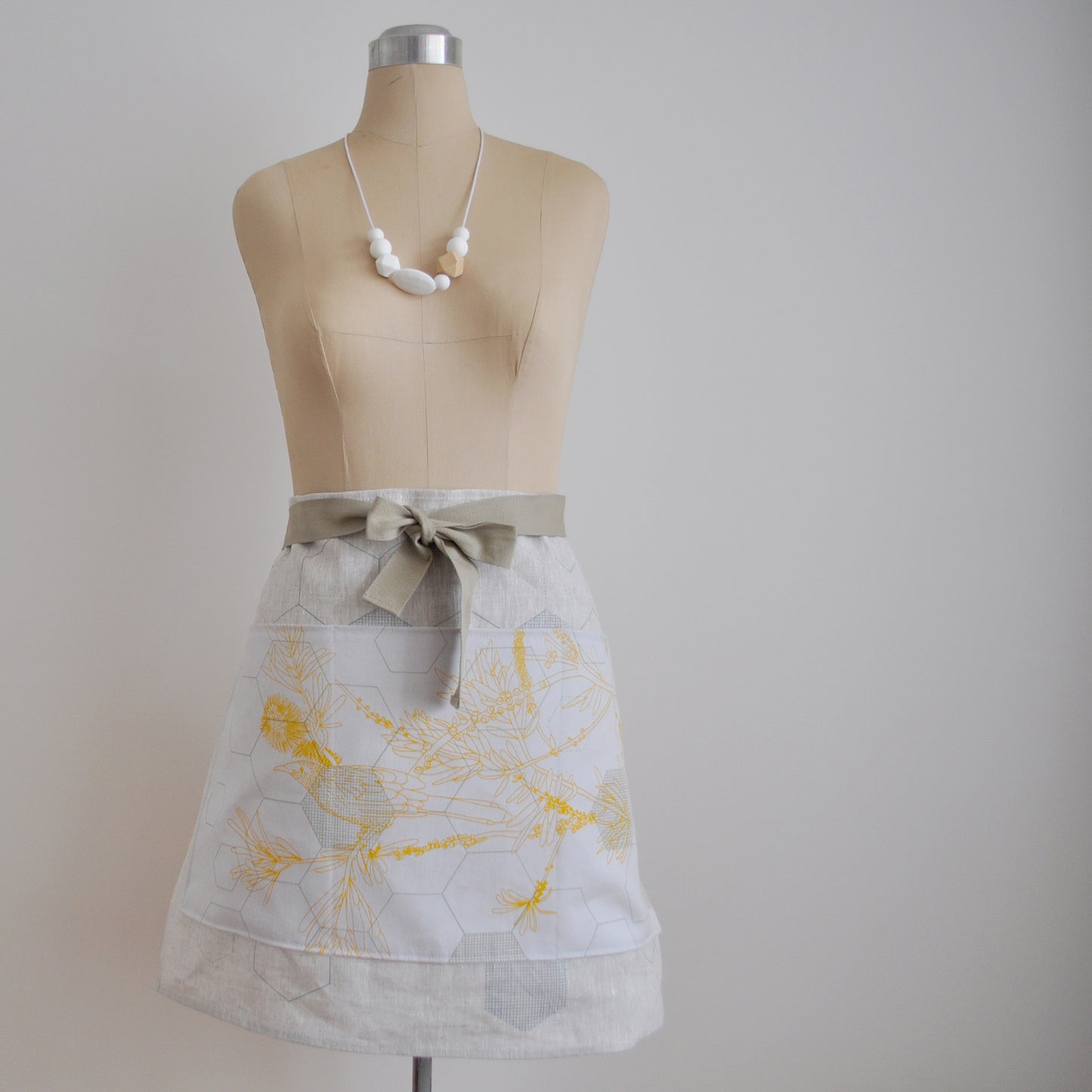 Pinch River waist apron / half apron No. 1 with pockets, on dressmakers dummy against a plain background. Front View.