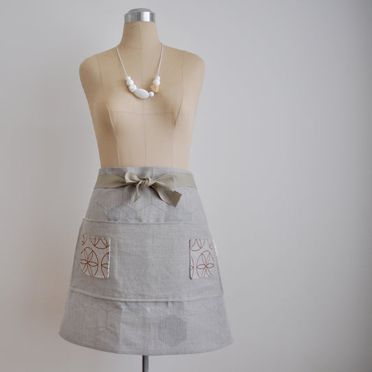 Pinch River waist apron / half apron No. 2 with pockets, on dressmakers dummy against a plain background. Front View.