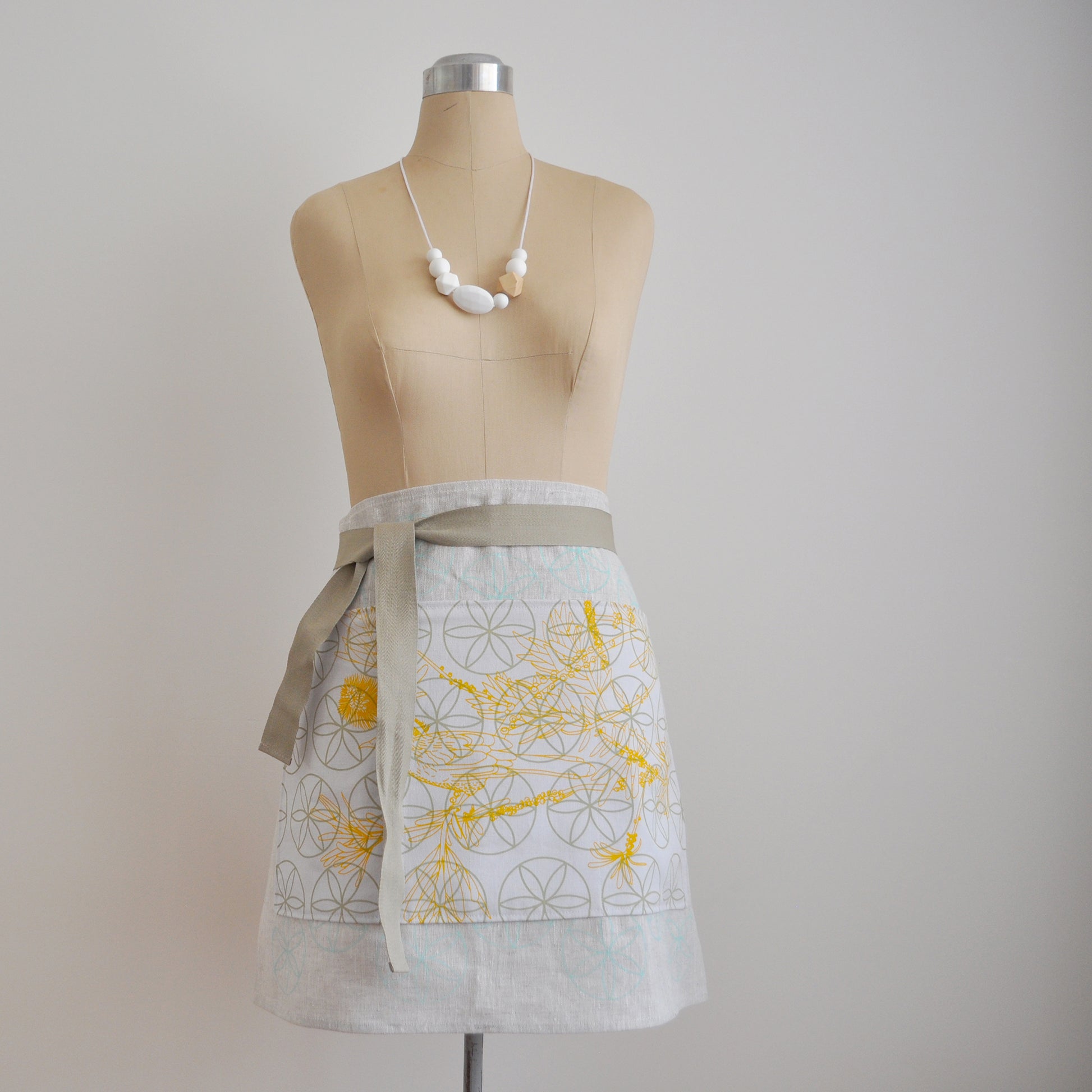 Pinch River waist apron / half apron No. 3 with pockets, on dressmakers dummy against a plain background. Front View.