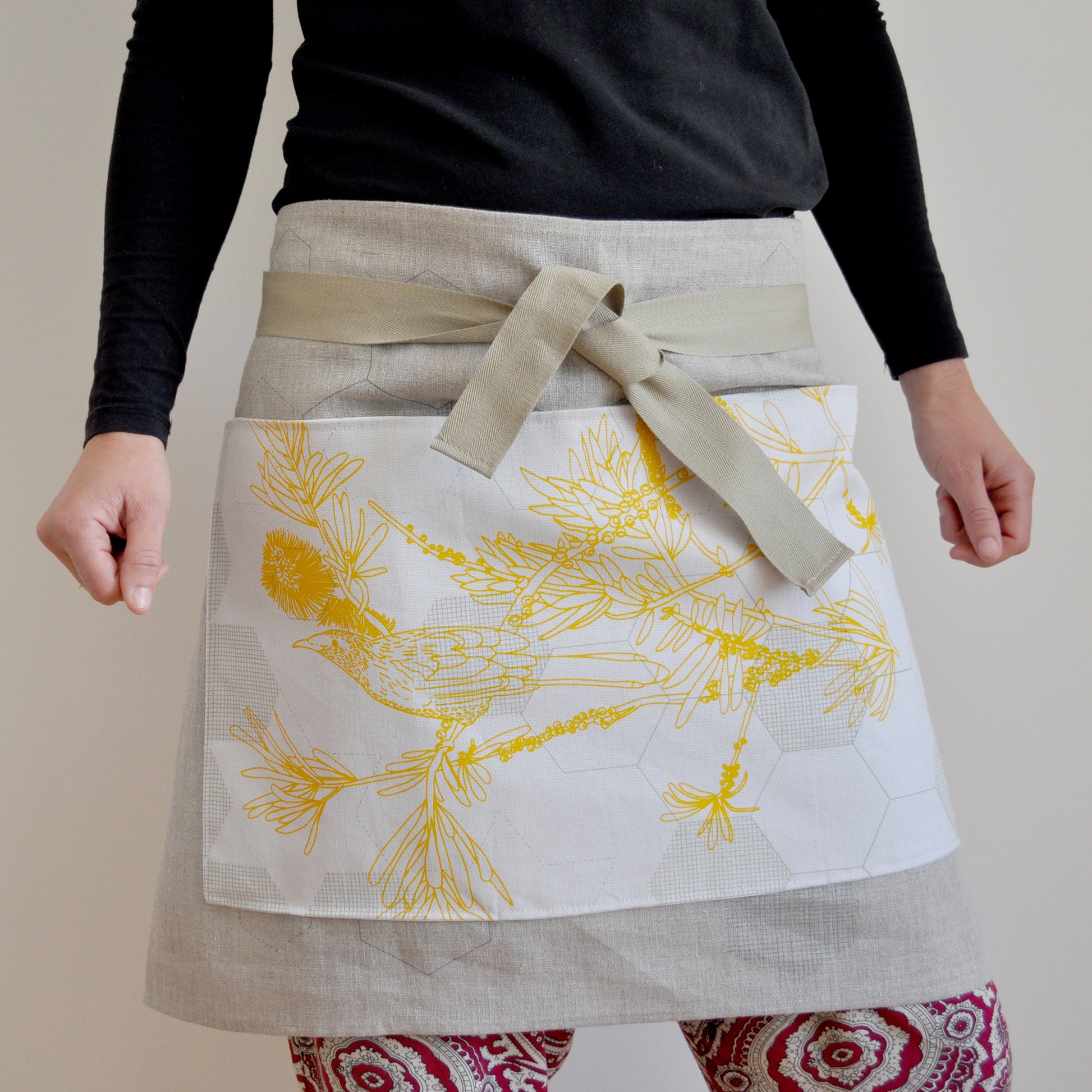 Model wearing Pinch River waist apron / half apron No. 4 with pockets, against a plain background. Front View. Pose #1.