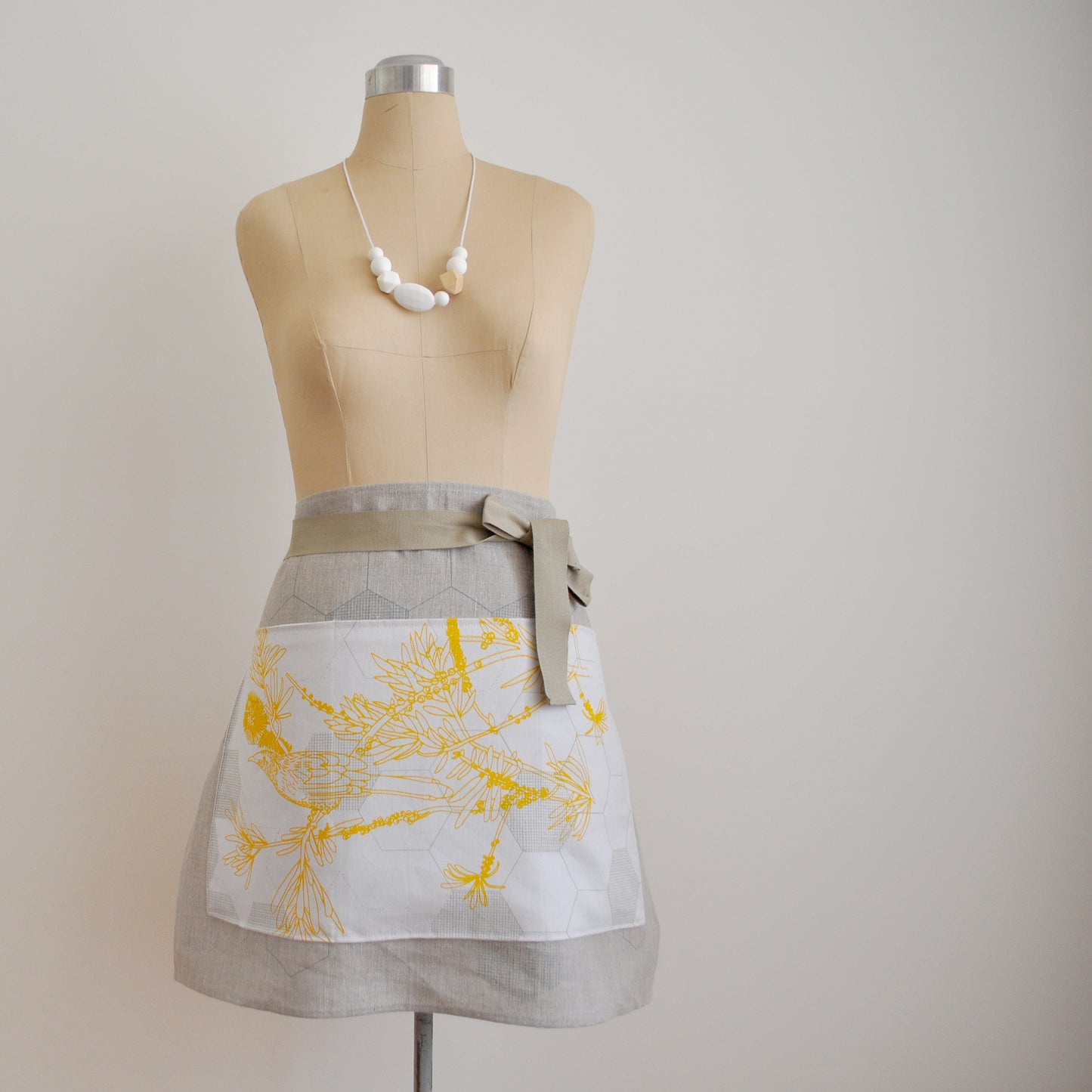 Pinch River waist apron / half apron No. 4 with pockets, on dressmakers dummy against a plain background. Front View.