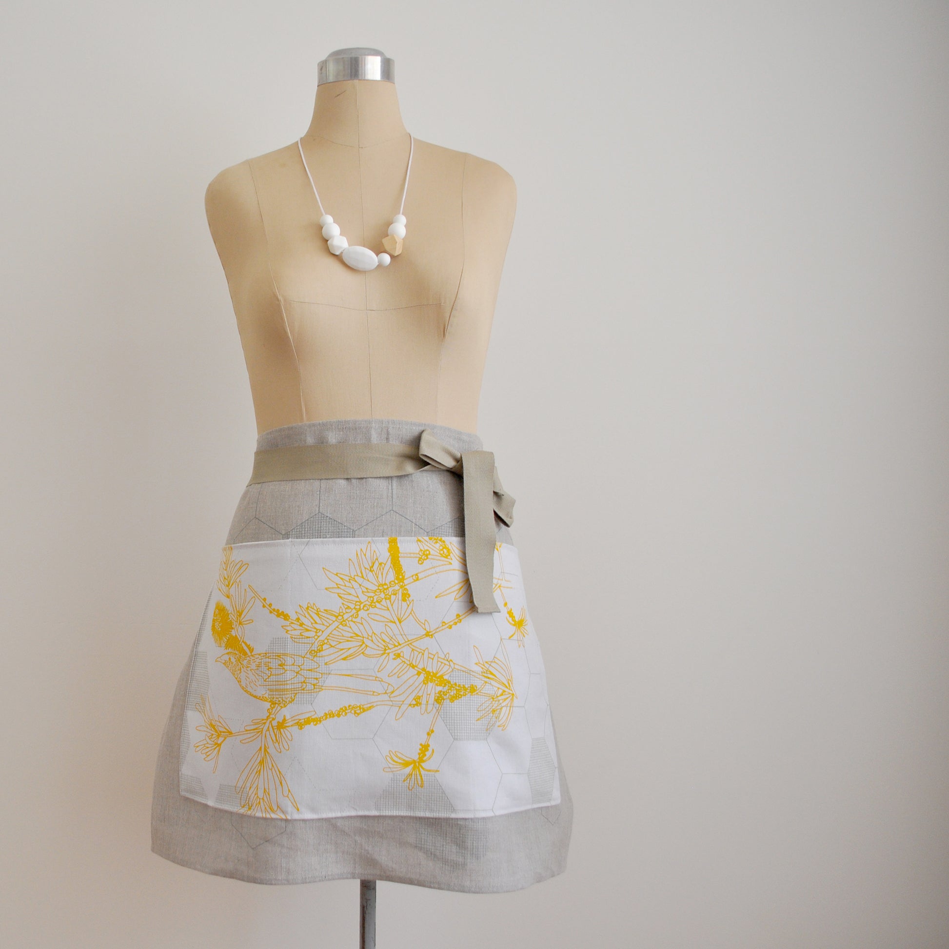 Pinch River waist apron / half apron No. 4 with pockets, on dressmakers dummy against a plain background. Front View.