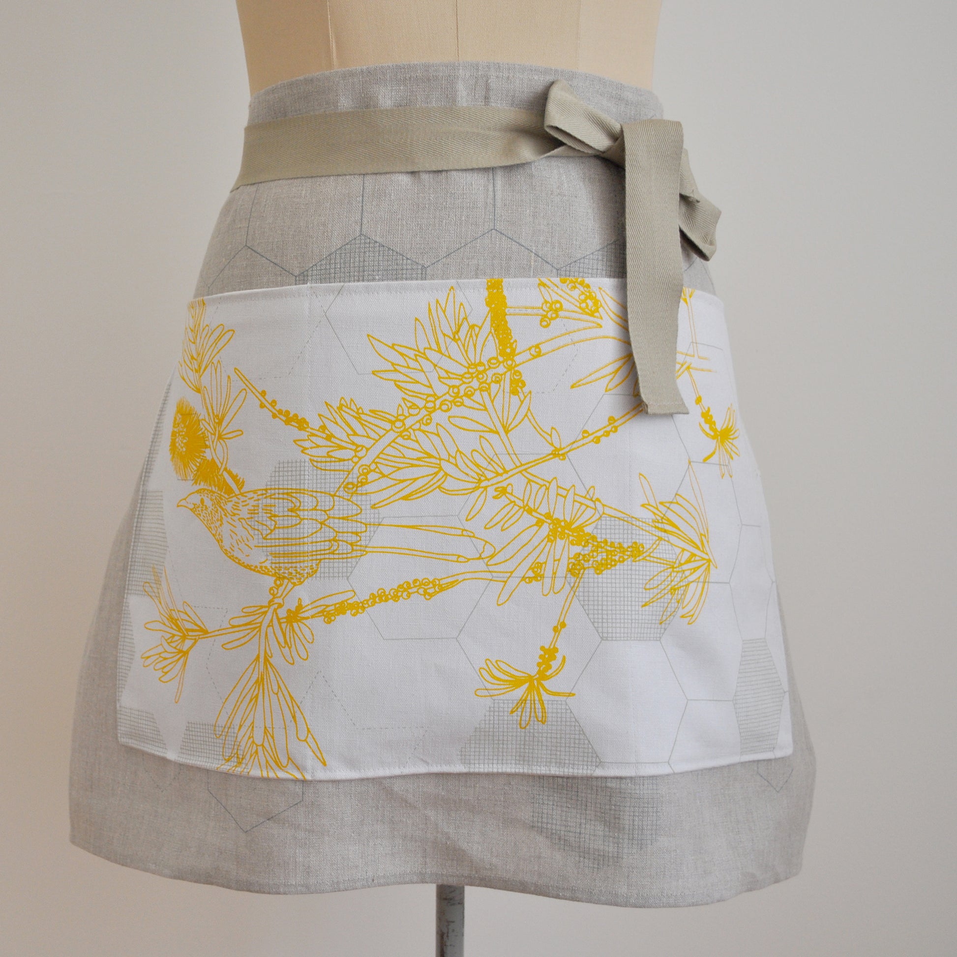 Pinch River waist apron / half apron No. 4 with pockets, on dressmakers dummy against a plain background. Front View. Close-up.