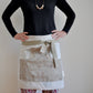 Model wearing Pinch River waist apron / half apron No. 5 with pockets, against a plain background. Front View.