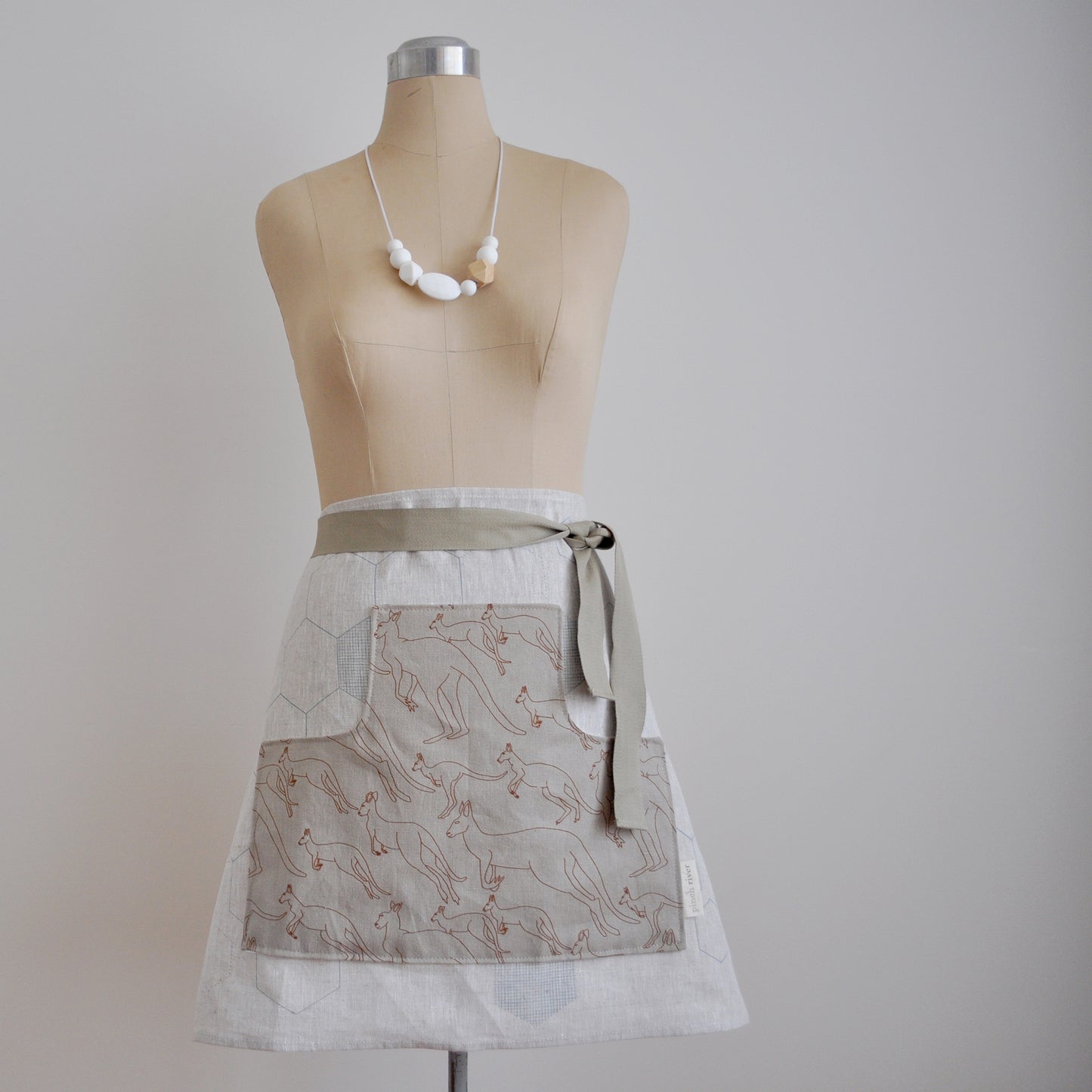 Pinch River waist apron / half apron No. 5 with pockets, on dressmakers dummy against a plain background. Front View.