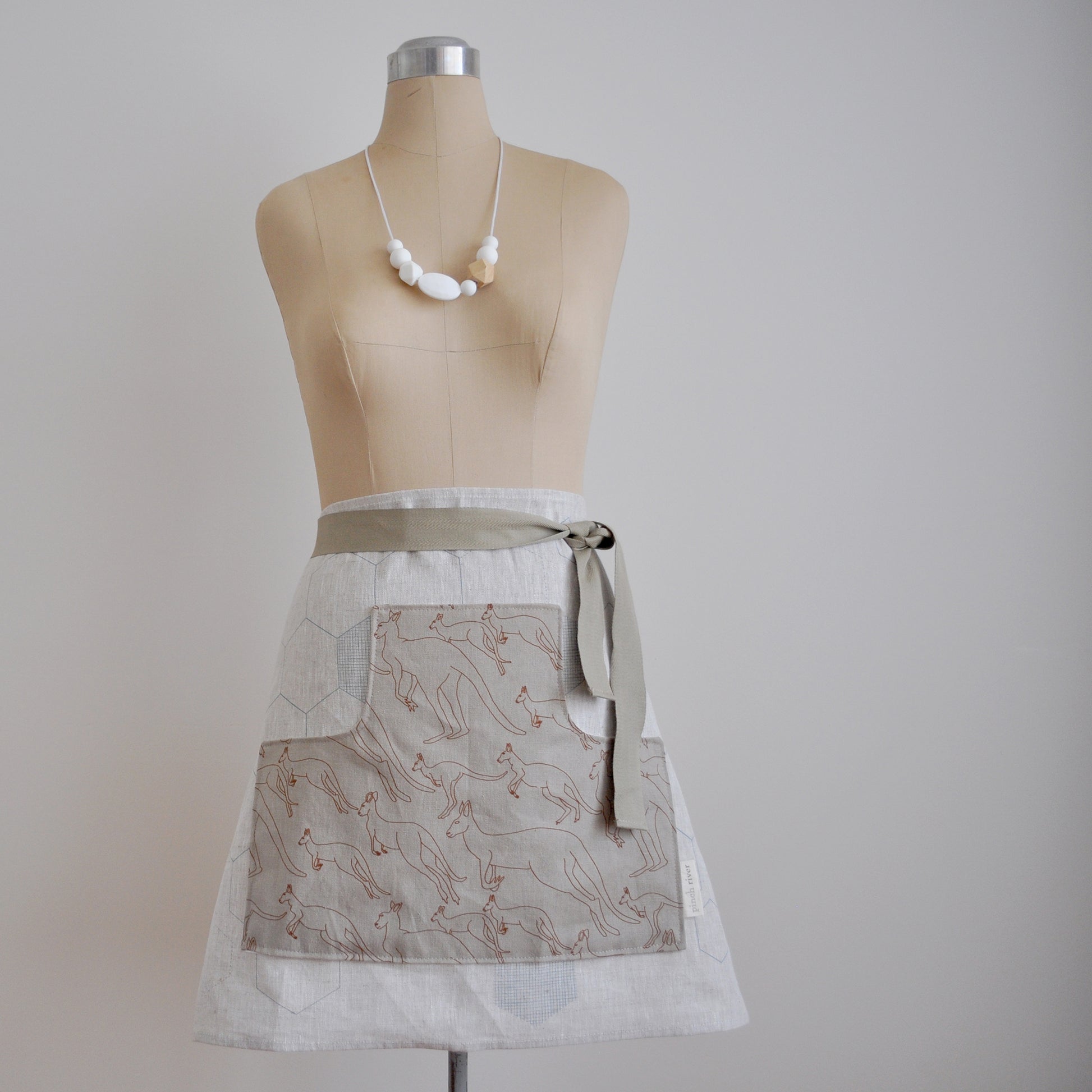 Pinch River waist apron / half apron No. 5 with pockets, on dressmakers dummy against a plain background. Front View.