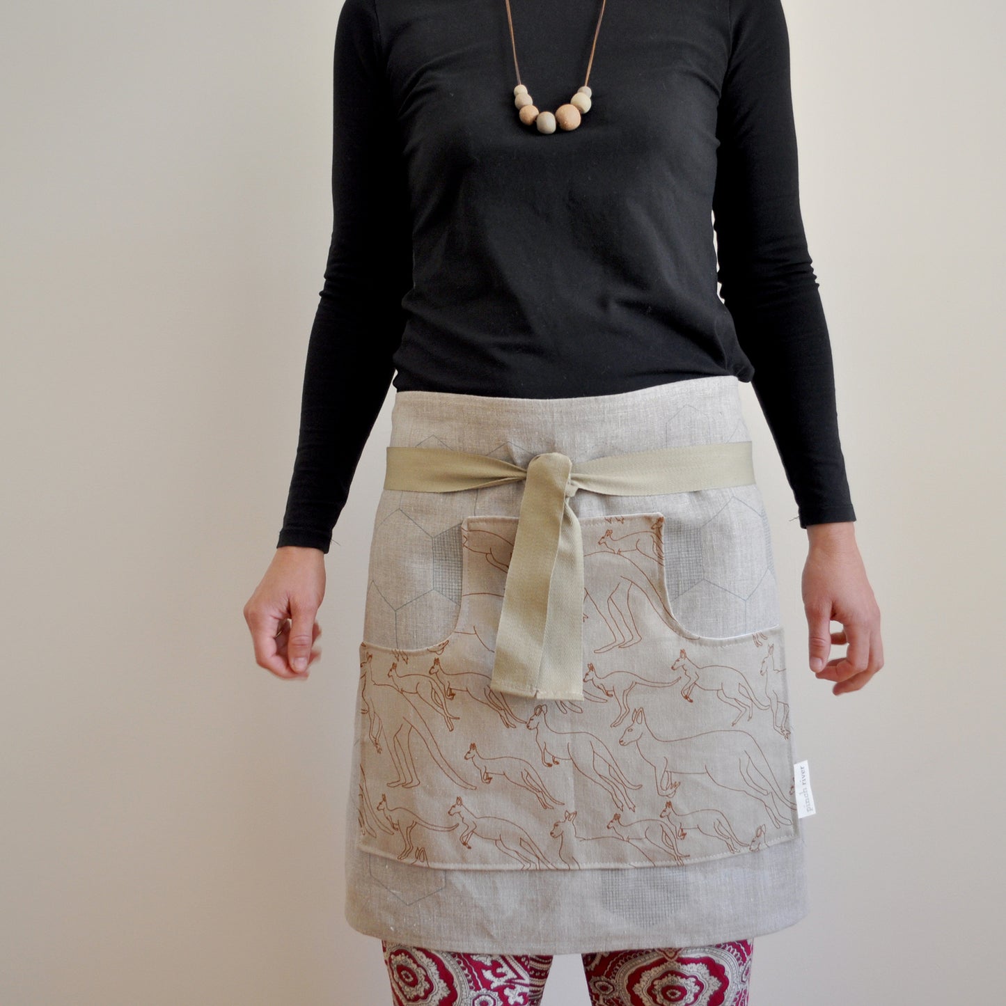 Model wearing Pinch River waist apron / half apron No. 6 with pockets, against a plain background. Front View.