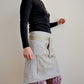 Model wearing Pinch River waist apron / half apron No. 6 with pockets, against a plain background. Side View.