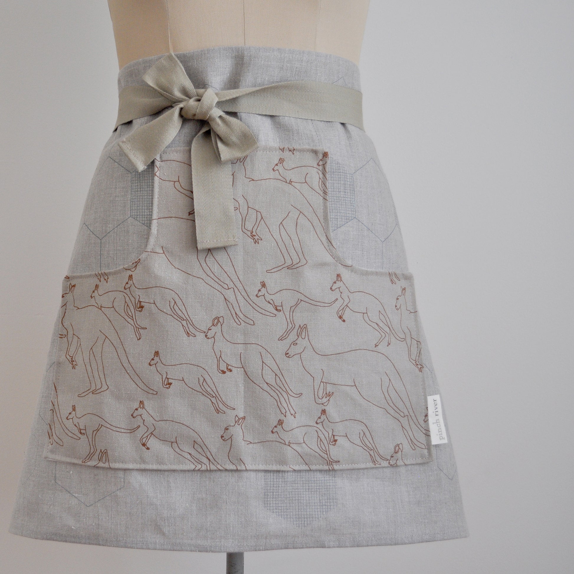 Pinch River waist apron / half apron No. 6 with pockets, on dressmakers dummy against a plain background. Front View. Close-up.