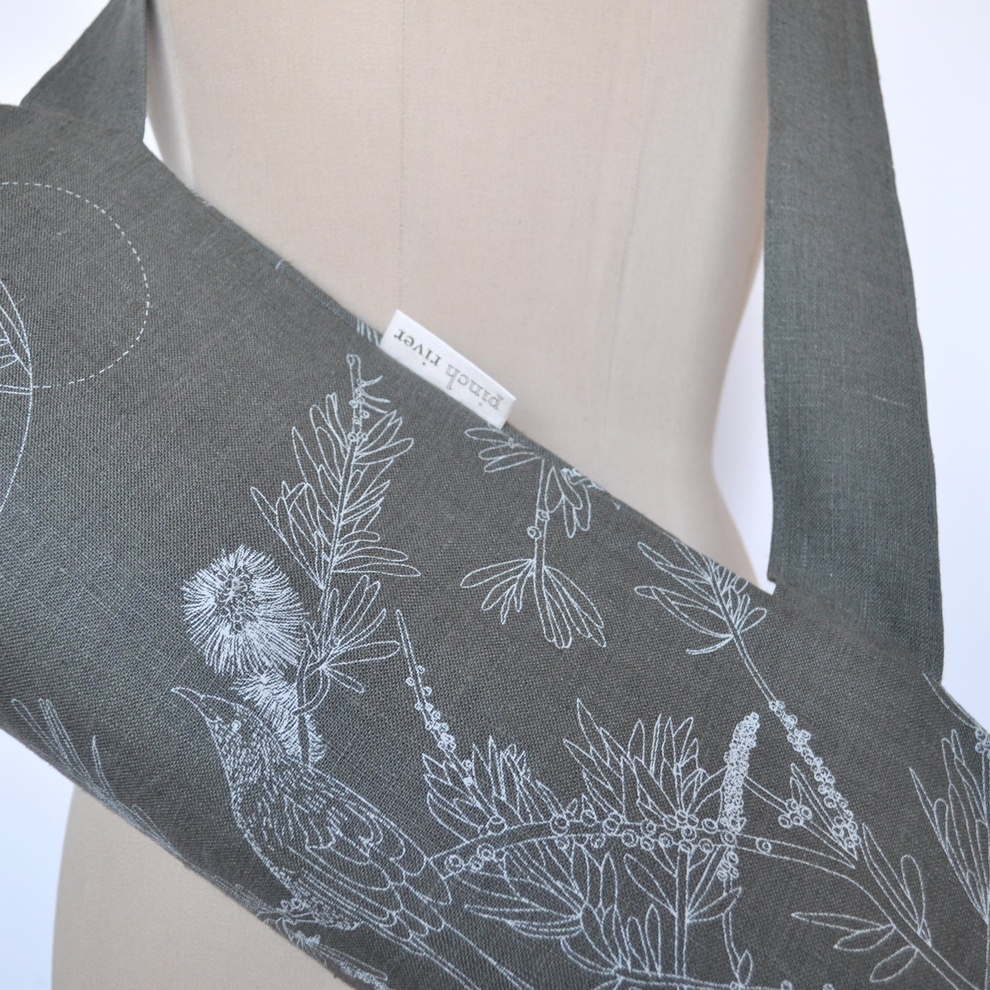 Pinch River yoga mat bag in Wattle Bird in the Bottle Brush print in Moss Green on Forest Green Linen (colourway 3), on dressmakers dummy. Close-up view.