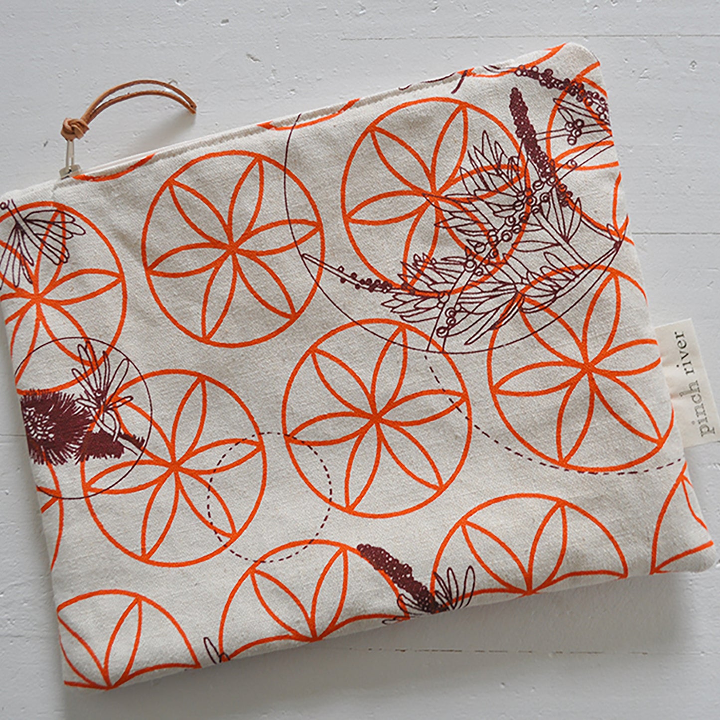 Pinch River zipper pouch featuring Wattle Bird in the Bottle Brush print in Wine Berry (colourway 1) overprinted with Flower of Life print in Fiery Orange (colourway 3). Top view.