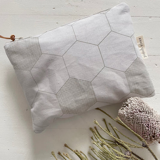 Pinch River zipper pouch featuring Honeycomb print in Moss Green (colourway 1). Top view. Product image is styled with Australian native flora.