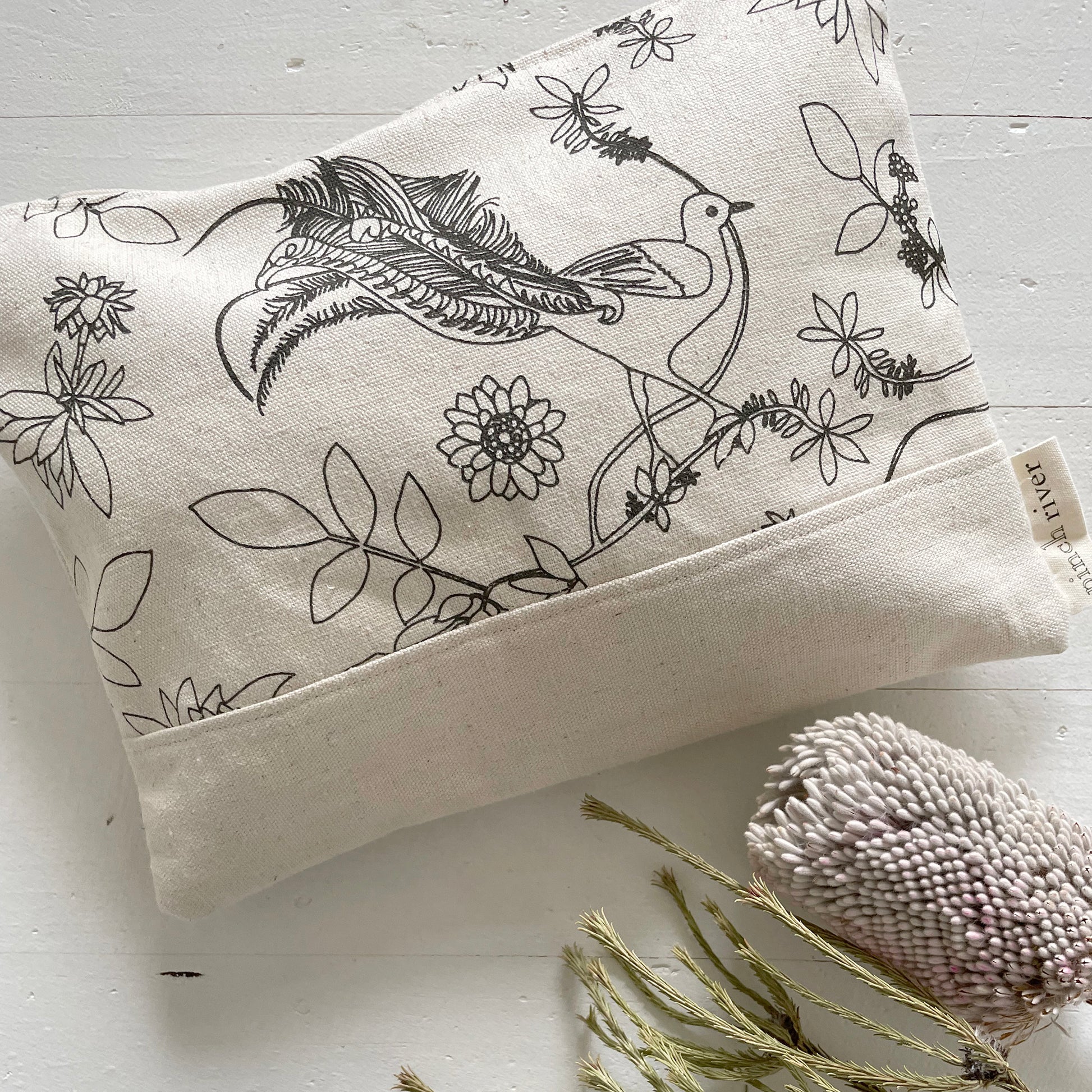 Pinch River zipper pouch featuring Lyrebird print in Gey Bark (colourway 1). Top view. Product image is styled with Australian native flora.