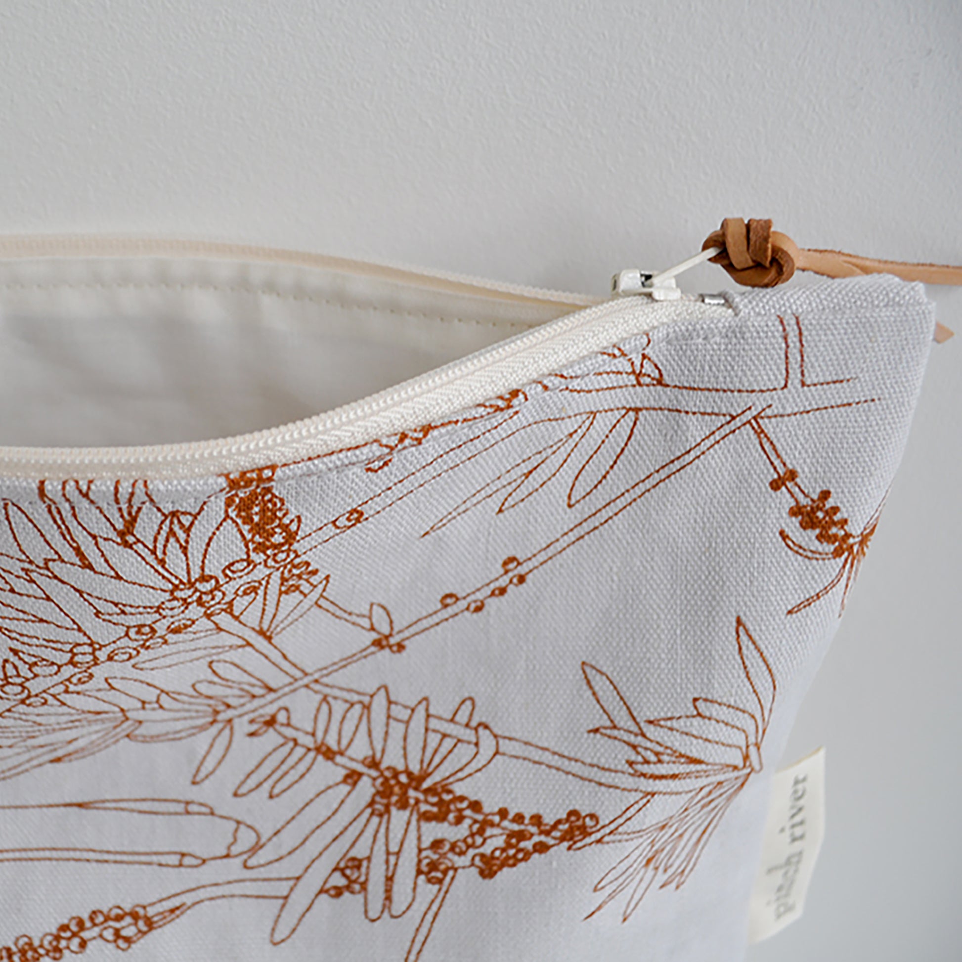 Pinch River zipper pouch featuring Wattle Bird print in Burnt Orange (colourway 2). Side view with zipper opened to show the pouch is fully lined.