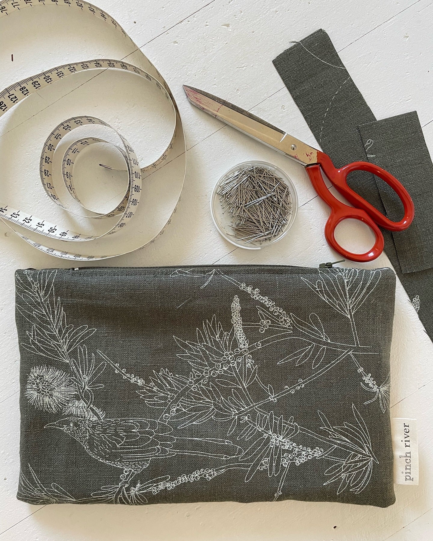Zipper Pouch with Wattle Bird print. Top View. Showing the finished product but with a tape measure, pins and scissors in the frame.